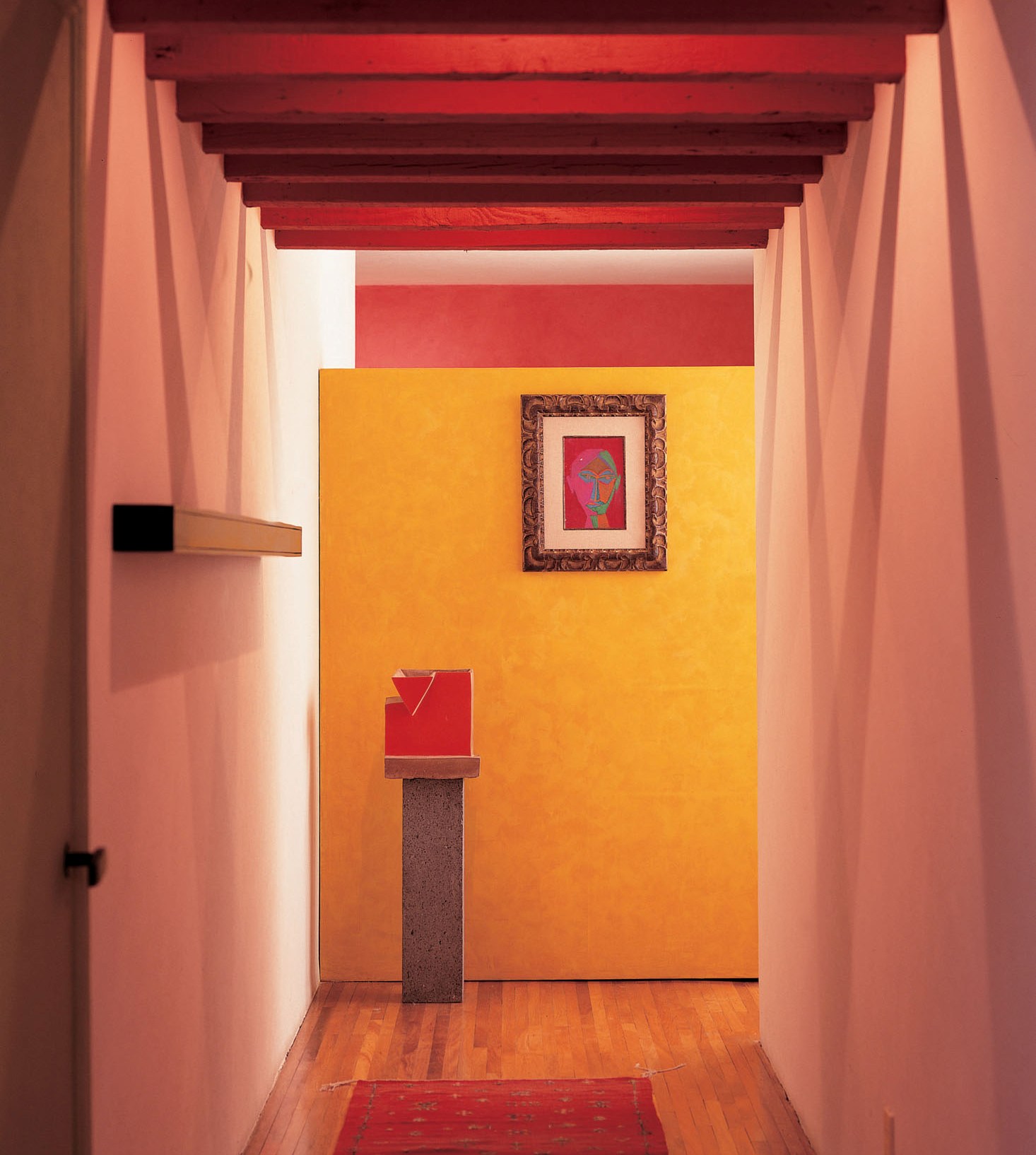 A cheerful Mexican color palette and strategic use of ceiling beams gave better proportion to a long, narrow corridor.